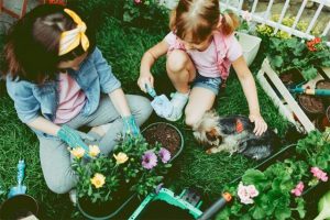 yorkshire terrier with girl and mother gardening e1527079954381