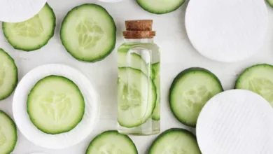 Homemade cucumber and chamomile facial cleanser in a bottle with cucumber slices and cotton pads