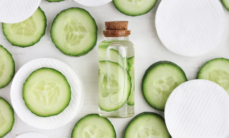 Homemade cucumber and chamomile facial cleanser in a bottle with cucumber slices and cotton pads