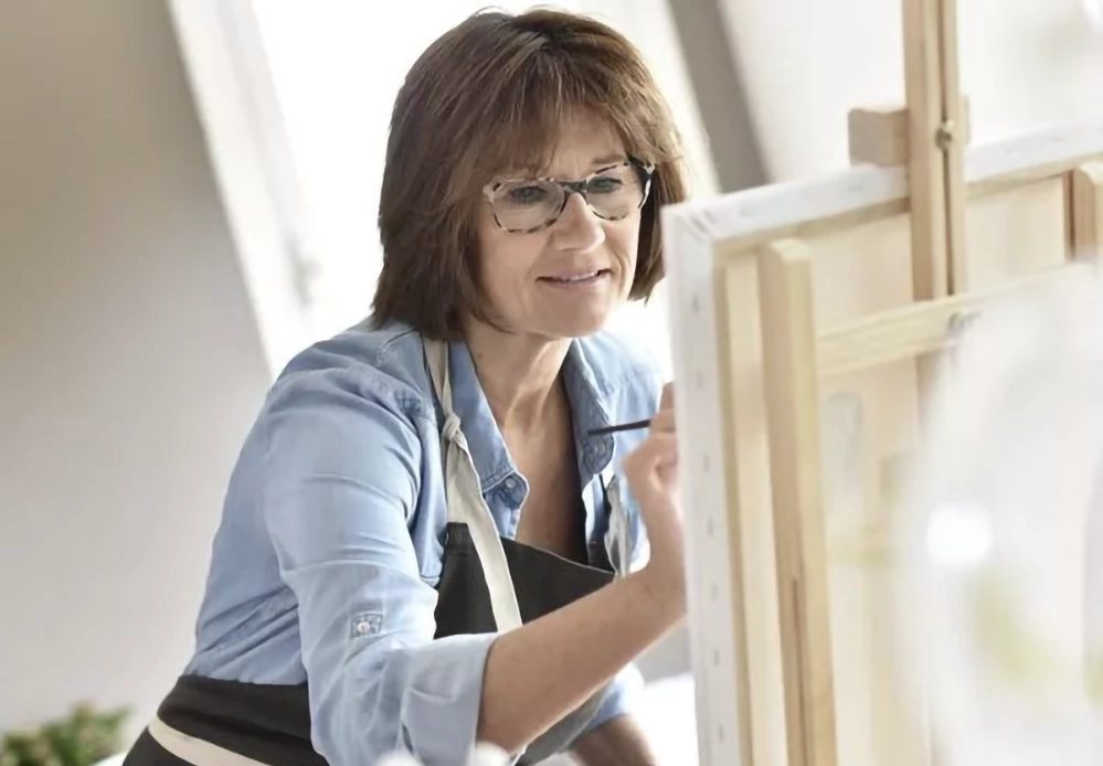 Older woman painting at an easel, focused and engaged in creative activity