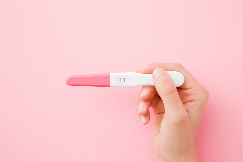 Young woman holding a positive pregnancy test