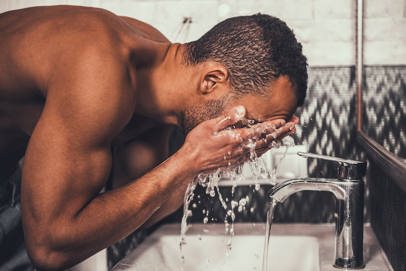african american man washing his face in the sink in the morning