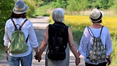 Three women walking hand in hand on a wildflower path on Mother's Day