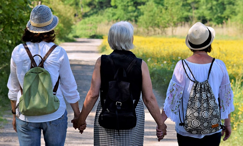 Three women walking hand in hand on a wildflower path on Mother's Day