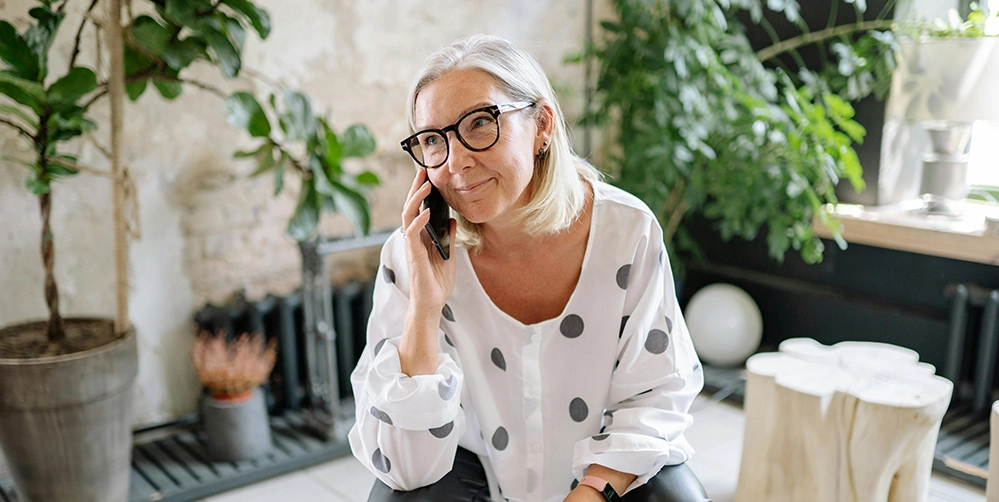 Older woman smiling while talking on the phone with a long-lost friend on Mother's Day