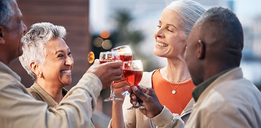 Four 50+ People Celebrating with Glasses of Wine Multiethnic group of adults laughing and toasting wine glasses outdoors together