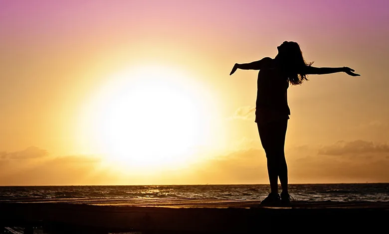 Ditch New Year's Resolutions 1 Woman on Pier Overlooking the Ocean at Sunrise