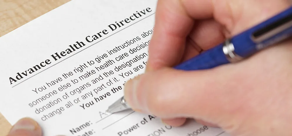 Why You Need a Living Will: 3 Expert-Backed Reasons to Protect Your Wishes 3 Hand holding pen, preparing to fill out a living will document.