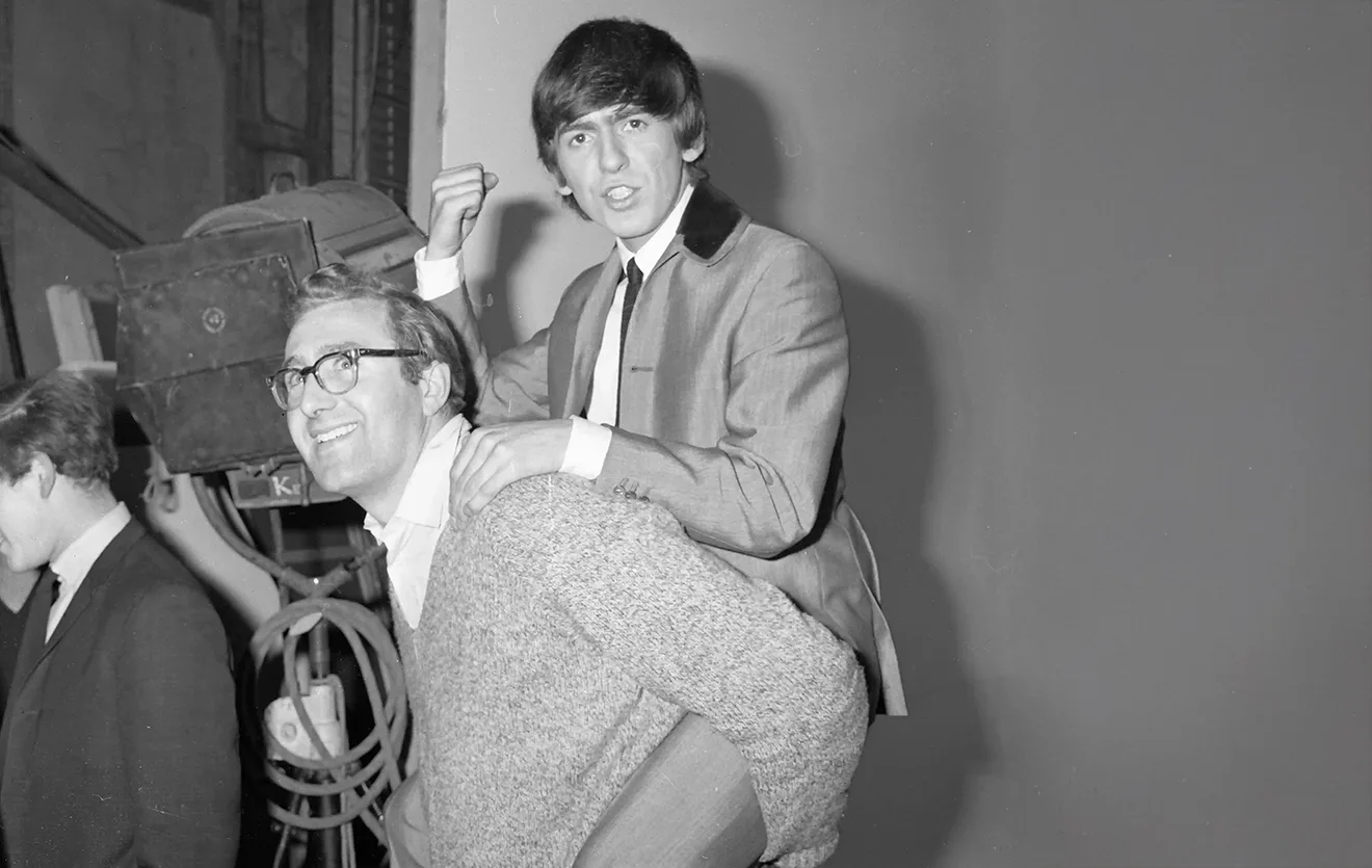 Living the Beatles Legend 4 George Harrison rides on Mal Evans’ back during a lighthearted moment.