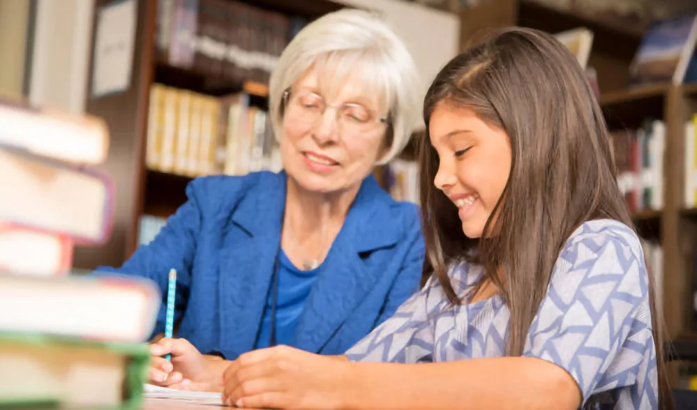 5 Ways You Can Support Seniors in Your Local Community 2 Senior shares knowledge by helping a young student with schoolwork.