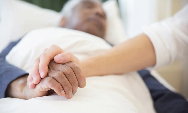 Improving Post-Hospital Outcomes for Older Adults 1 Older adult patient resting in a hospital bed, visitor holding his hand in support.