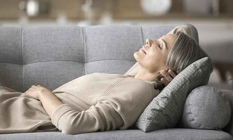 Top 4 Restful Sleep Strategies Tailored for the 50+ Body 1 A 50+ woman napping on the couch, illustrating the importance of rest in healthy aging.