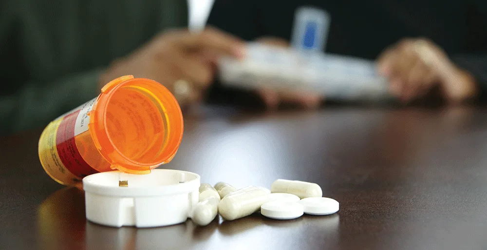 Improving Post-Hospital Outcomes for Older Adults 3 Open bottle of pills with people in the background, representing the role of medication errors in hospital readmissions among older adults.