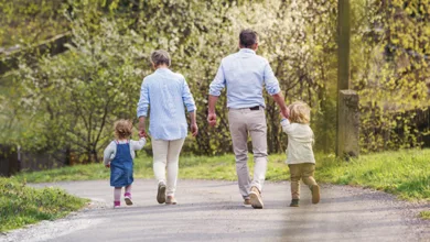 Are Grandparents the Answer to America's Childcare Crisis? 1 Grandparents walking hand-in-hand with toddler grandchildren on a country road in spring, symbolizing multigenerational support in childcare.