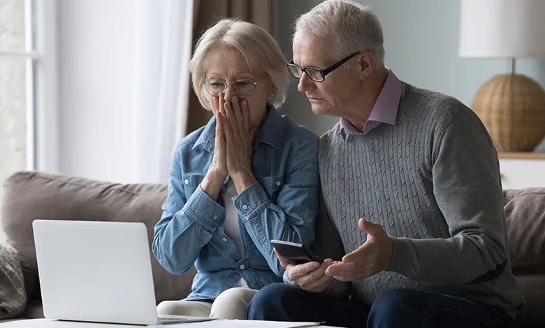 Think You’d Never Fall for a Scam? Think Again! 1 A shocked older couple is staring at a laptop, reacting to the possibility of fraud, financial loss, or online scams.