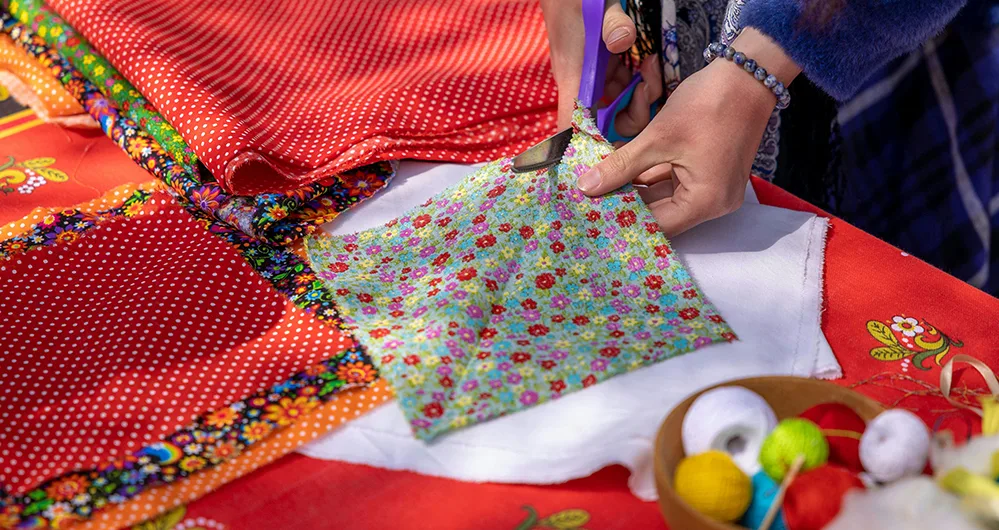 4 Creative Techniques for Unique Quilting Patterns 2 Woman cutting colorful patterned fabric pieces for quilt preparation, demonstrating fabric selection techniques.