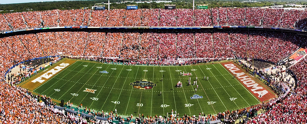 State Fair of Texas 2025 5 Aerial view of a packed Cotton Bowl stadium during the Red River Rivalry game, showing Texas fans in burnt orange and Oklahoma fans in red filling every seat.