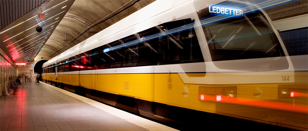 Big Texas and DART 2 DART light rail train approaching station platform with modern design and green line branding