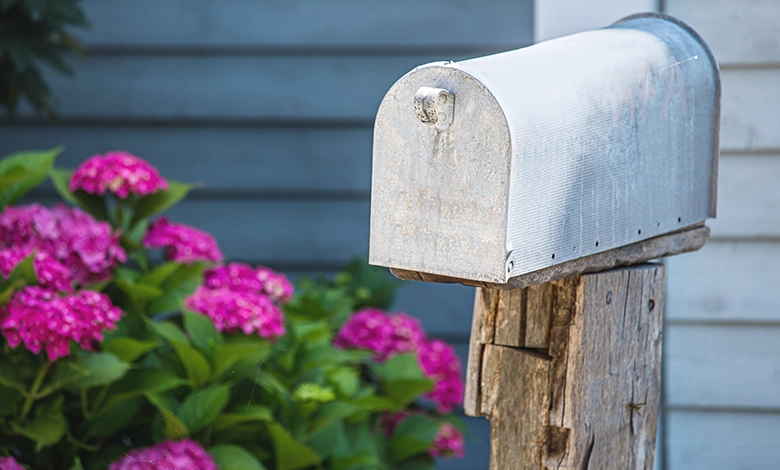 Social Security Ending Paper Checks in 2025 1 Traditional white mailbox on wooden post with flowers, representing the end of Social Security paper check delivery.