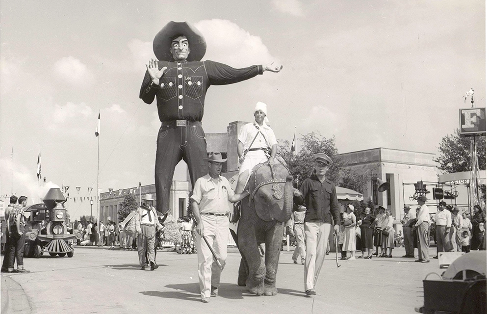 State Fair of Texas 2025 2 Vintage black and white photo of Big Tex at the 1952 State Fair with an elephant and fairgoers showing the classic carnival atmosphere of the early years.
