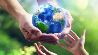Living Greener for Your Grandchildren 5 Older hands carefully passing the Earth globe to younger hands reaching up to receive it, representing environmental legacy and intergenerational responsibility for the planet.