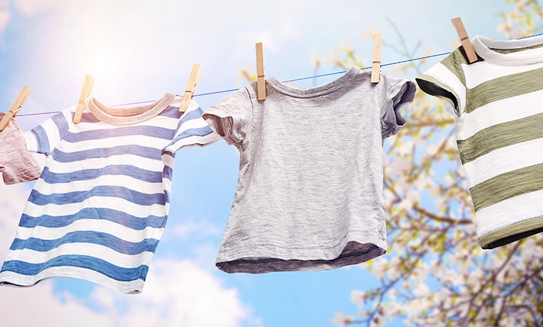 How My Depression-Era Parents Taught Me Sustainable Living 1 Children's clothes hanging on an outdoor clothesline with wooden clothespins against a blue sky and trees, representing sustainable living practices from the Depression era.