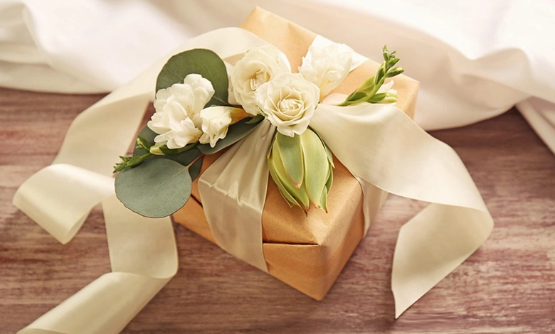 5 Thoughtful Wedding Gift Ideas That Go Beyond the Usual 1 Elegant gold wrapped wedding gift with white roses and ribbon