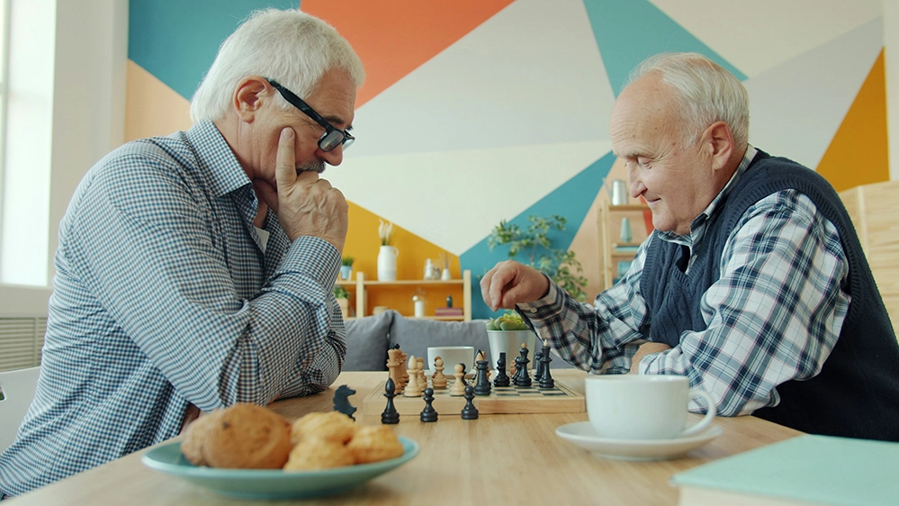 Two older men playing chess together, illustrating how shared games can build lasting friendships in retirement