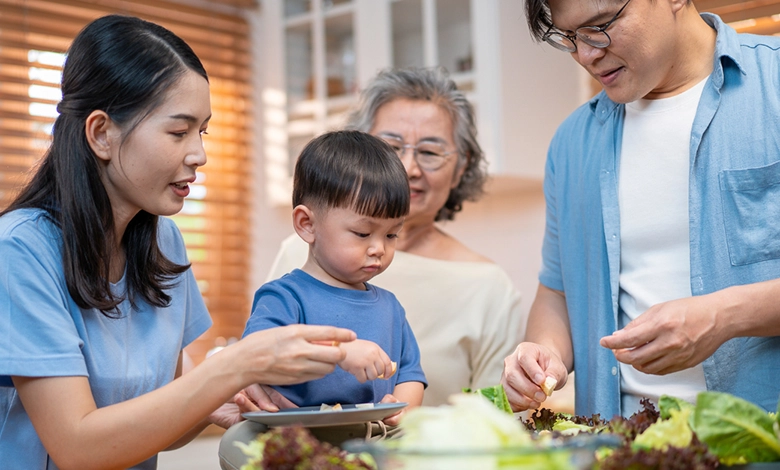 How to Create a Comfortable Home for Multigenerational Living 1 Three generations cooking together in open kitchen of multigenerational home with grandmother parents and child preparing meal