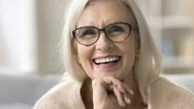 Smiling senior woman with glasses showing healthy white teeth, representing successful dental care in golden years