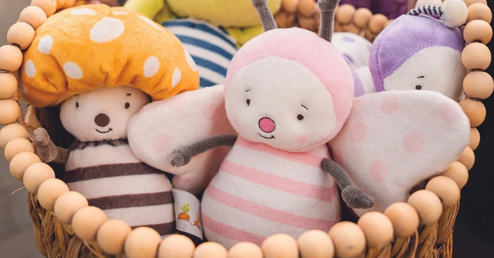 Colorful stuffed animal toys organized in wooden basket for baby comfort and play