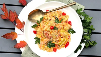 Creamy Chicken Artichoke Skillet: One-Pot Wonder 2 Creamy chicken artichoke bow tie pasta in white bowl with cherry tomatoes parsley garnish and autumn leaves