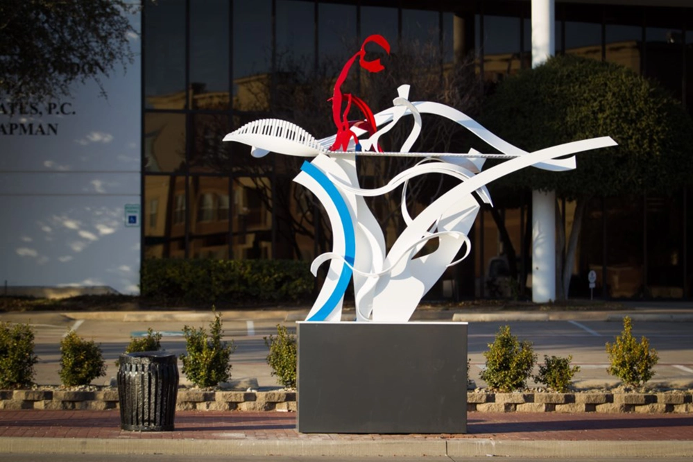 New DART Silver Line: The Easy Way to DFW Airport 5 Abstract white and blue ribbon sculpture with red figure playing piano representing music and movement public art at DART Silver Line station