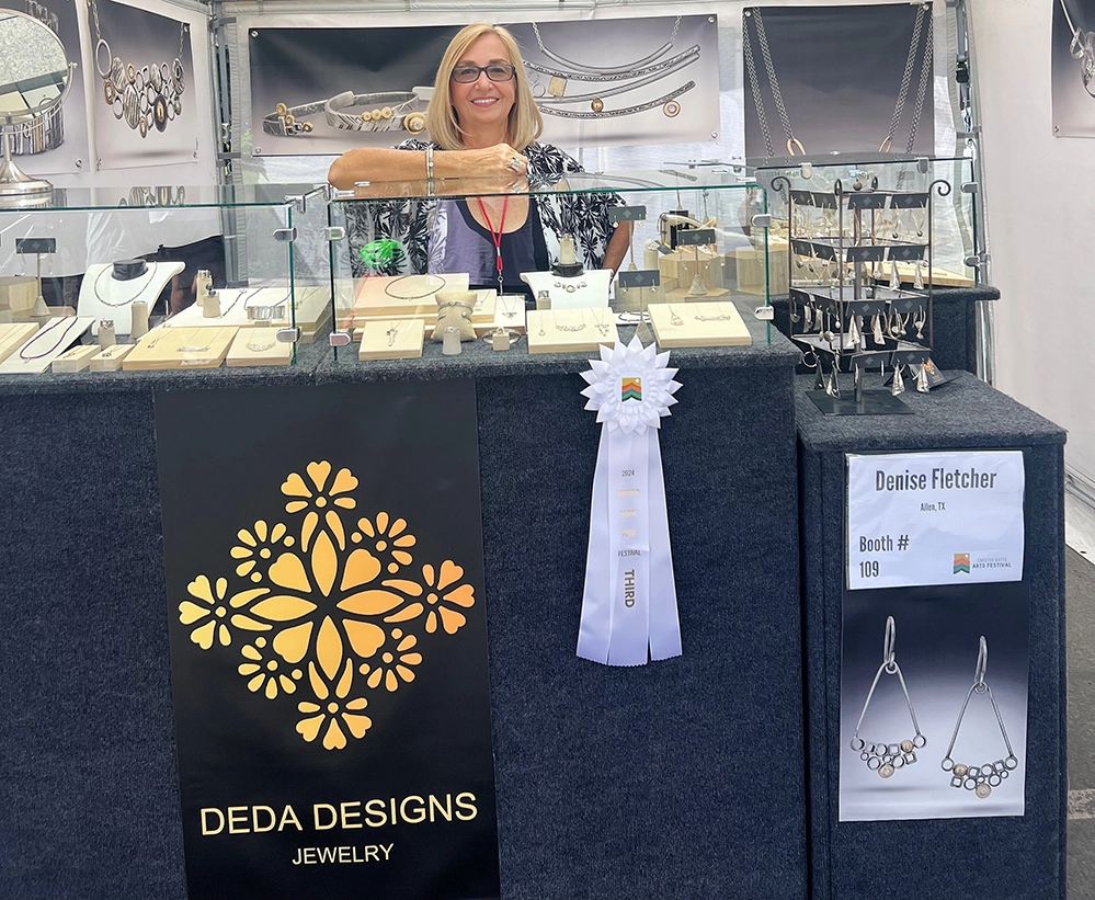 Turning Passion Into Purpose After 50: 3 creatives living their dream 3 Denise Fletcher at DEDA Designs jewelry booth at art festival with award ribbon displaying handmade metalwork jewelry