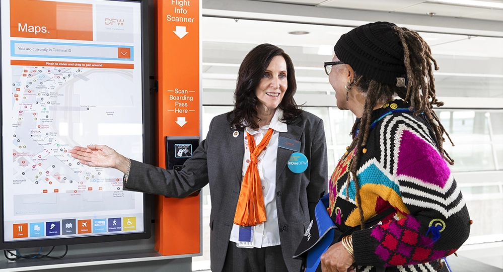 DFW Ambassador volunteer assists a passenger using the airport’s digital map