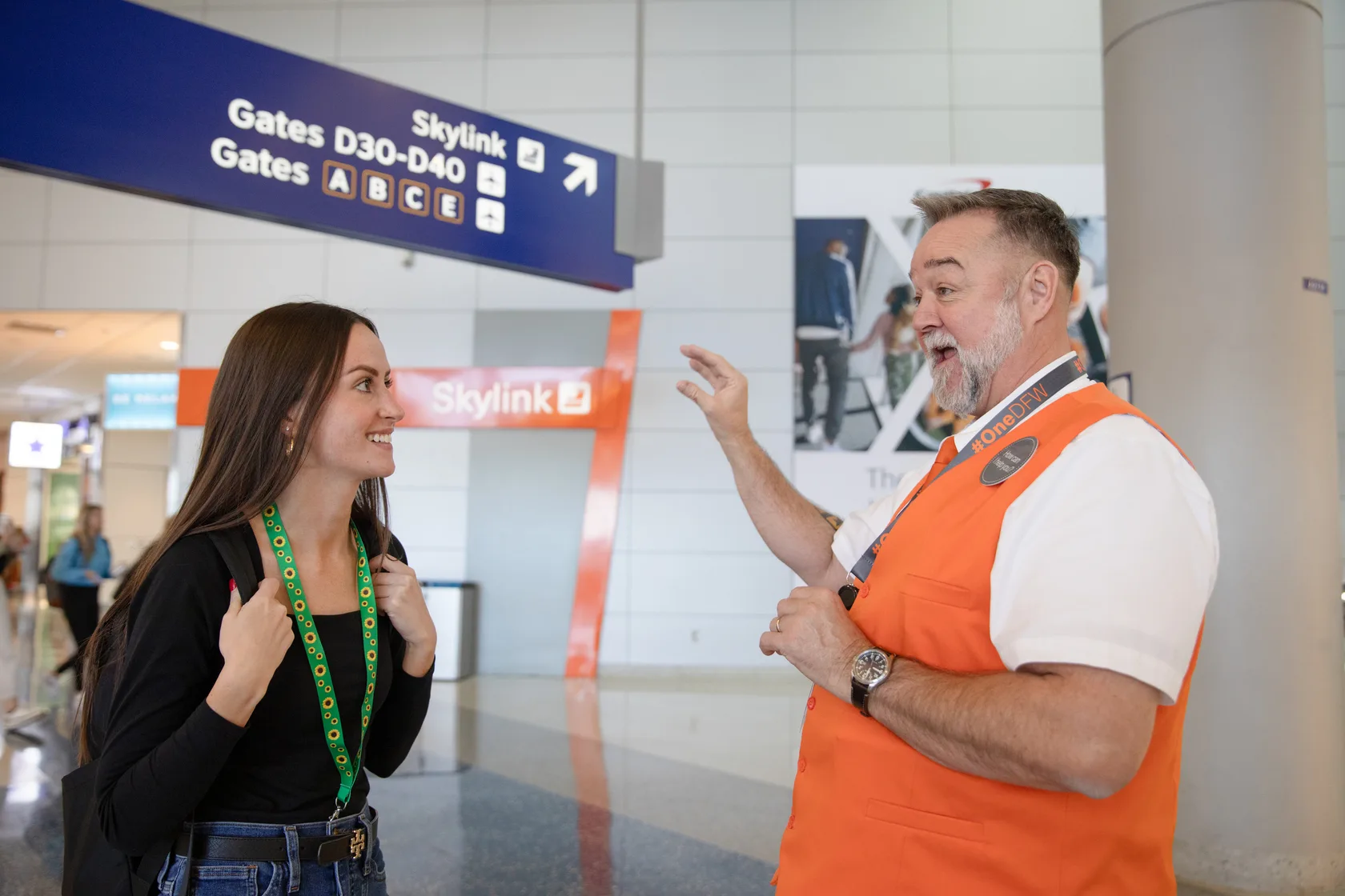 A DFW Ambassador helps a traveler wearing the Sunflower Lanyard, which discreetly signals the need for extra patience and support.
