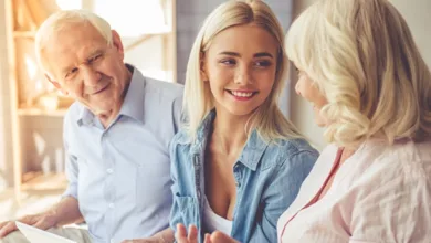 Multi-generational family smiling together discussing estate planning with adult daughter and elderly parents showing positive family communication
