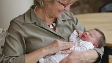 Grandmother lovingly holding newborn grandbaby demonstrating the bond between grandparents and grandchildren