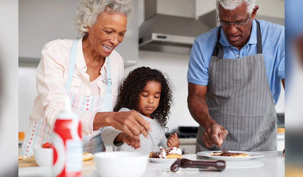 Grandparents and granddaughter baking together in kitchen teaching family traditions and bonding through cooking activities