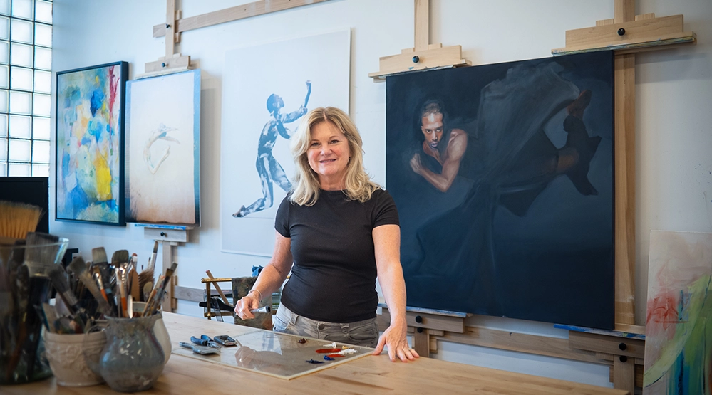 Turning Passion Into Purpose After 50: 3 creatives living their dream 8 Lisa Temple in her McKinney Texas art studio with portrait and abstract paintings on easels showing her artistic versatility