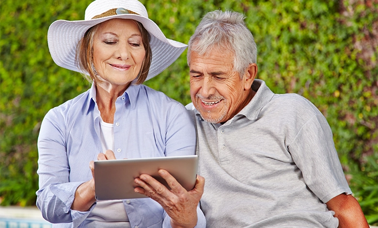 Senior couple outdoors using tablet together learning technology and staying connected