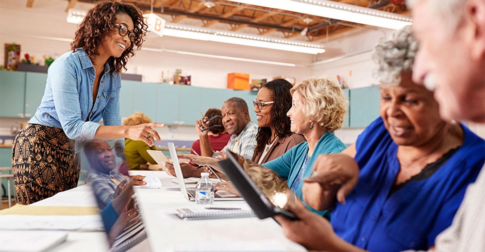 Diverse group of seniors in technology class with instructor learning digital skills and computer basics