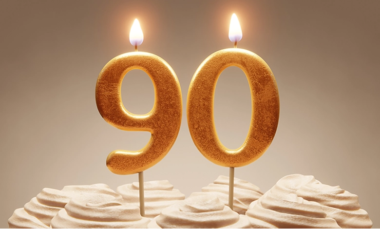 Golden number candles forming “90” atop a frosted cake, symbolizing Social Security’s 90th anniversary celebration.