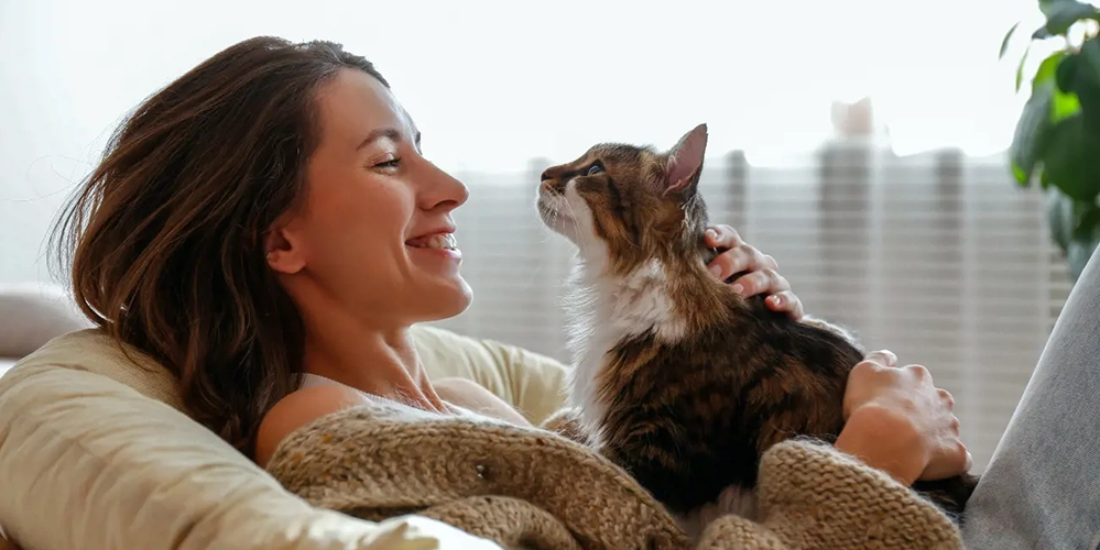 Woman relaxing on couch with tabby cat showing how cats improve cognitive function and reduce stress for brain health