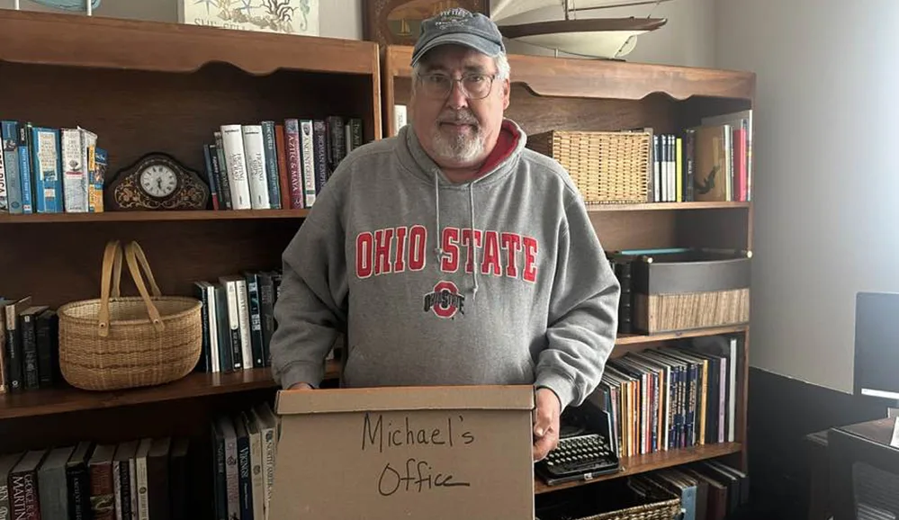 Moving After 50 2 Man holding moving box in front of a bookcase