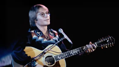 John Denver's 'Take Me Home, Country Roads' Hits 55 This Year 1 John Denver on stage playing guitar and singing