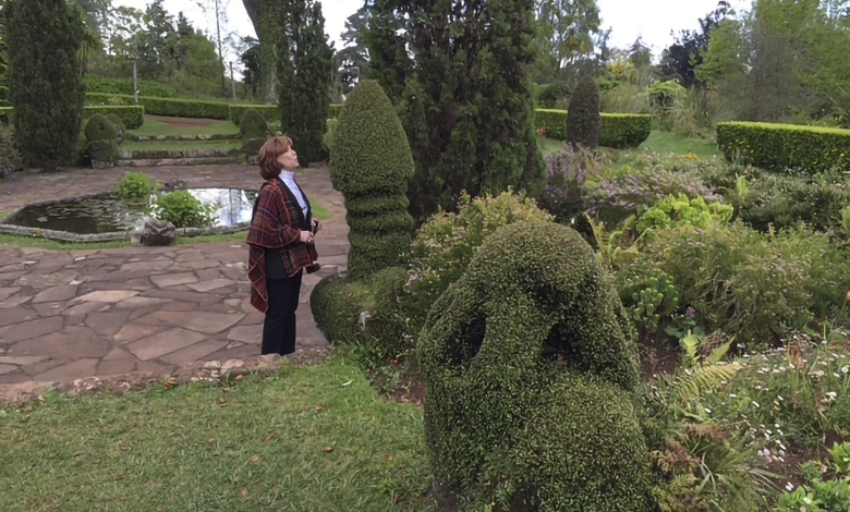 Diane Heiler, 82, author and speaker on aging with vitality, standing in garden with topiary sculptures
