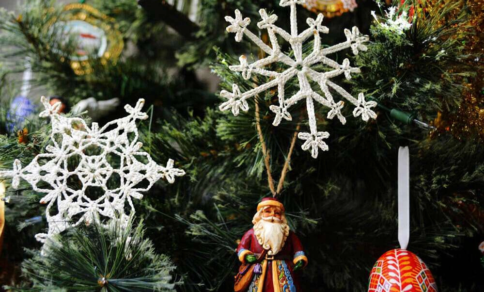 Hand-crocheted white snowflake Christmas ornaments made by great aunt hanging on tree 50 years later