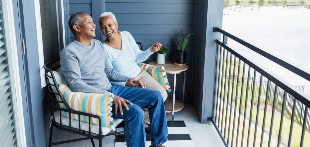 A senior couple laughing together on a balcony