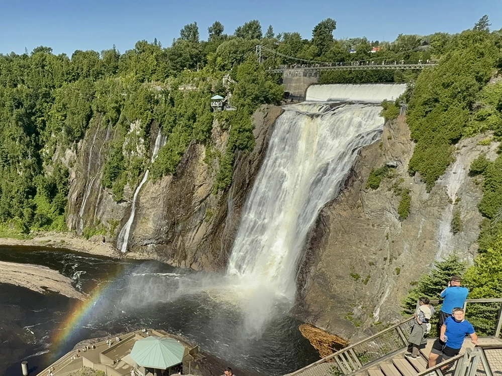 Montmorency Falls in Parc de la Chute-Montmorency near Québec City, with rainbow mist and visitors on a viewing platform.